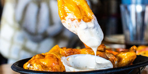 Chicken Wing Being Dipped into Blue Cheese Sauce